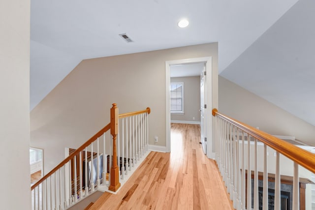 hall featuring an upstairs landing, wood finished floors, baseboards, and recessed lighting