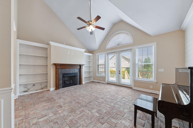 living area with ceiling fan, a tile fireplace, brick flooring, baseboards, and high vaulted ceiling