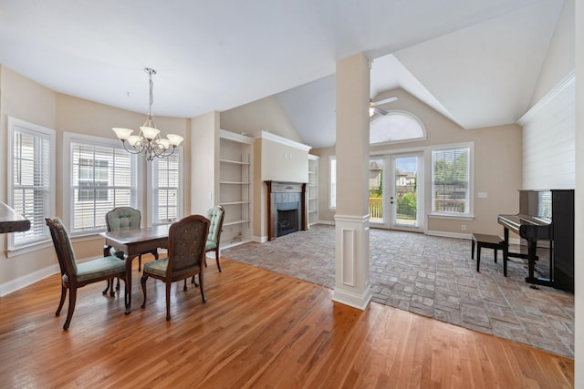 dining room featuring a fireplace, a chandelier, light wood finished floors, baseboards, and a ceiling fan