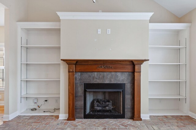 detailed view of a fireplace, baseboards, and built in shelves