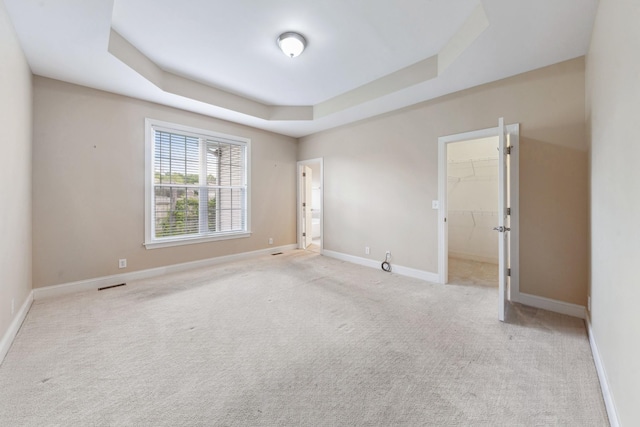 carpeted empty room with a raised ceiling and baseboards