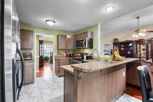 845 Nandina Ct, Clarksville, TN 37043 - kitchen with stainless steel appliances, a peninsula, a kitchen bar, a sink, and light marble finish flooring