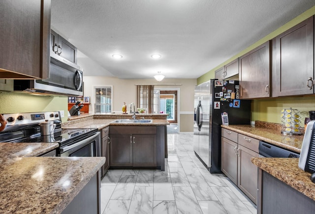 845 Nandina Ct, Clarksville, TN 37043 - kitchen featuring appliances with stainless steel finishes, a peninsula, light marble finish flooring, a sink, and dark brown cabinetry