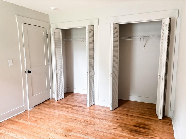 400 Circle Dr, Estill Springs, TN 37330 - unfurnished bedroom featuring two closets, light wood-type flooring, and baseboards