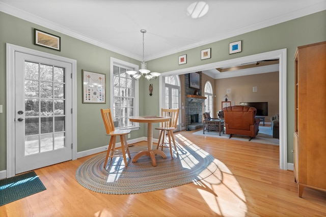 1130 Crater Hill Dr, Nashville, TN 37215 - dining area with light wood-style flooring, crown molding, a chandelier, a stone fireplace, and baseboards