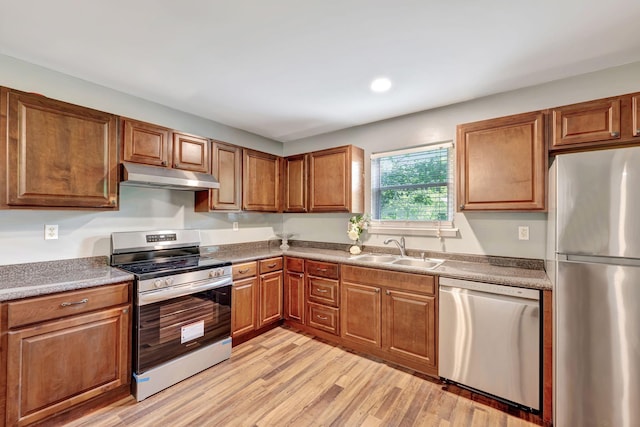2290 Petway Rd, Ashland City, TN 37015 - kitchen featuring stainless steel appliances, a sink, under cabinet range hood, light wood-style floors, and brown cabinetry