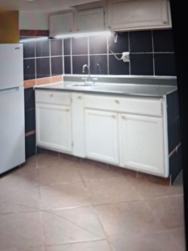 438 Tampa Dr, Nashville, TN 37211 - kitchen with freestanding refrigerator, a sink, white cabinetry, decorative backsplash, and light tile patterned flooring