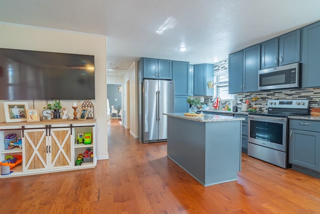 1689 Pleasant Ridge Rd, Huntland, TN 37345 - kitchen featuring stainless steel appliances, blue cabinetry, a kitchen island, light wood-type flooring, and decorative backsplash