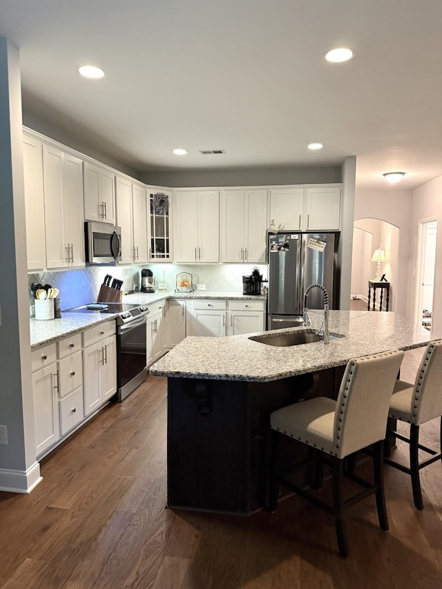 107 Auxley Ct, White House, TN 37188 - kitchen featuring appliances with stainless steel finishes, dark wood-style floors, a sink, glass insert cabinets, and a breakfast bar area