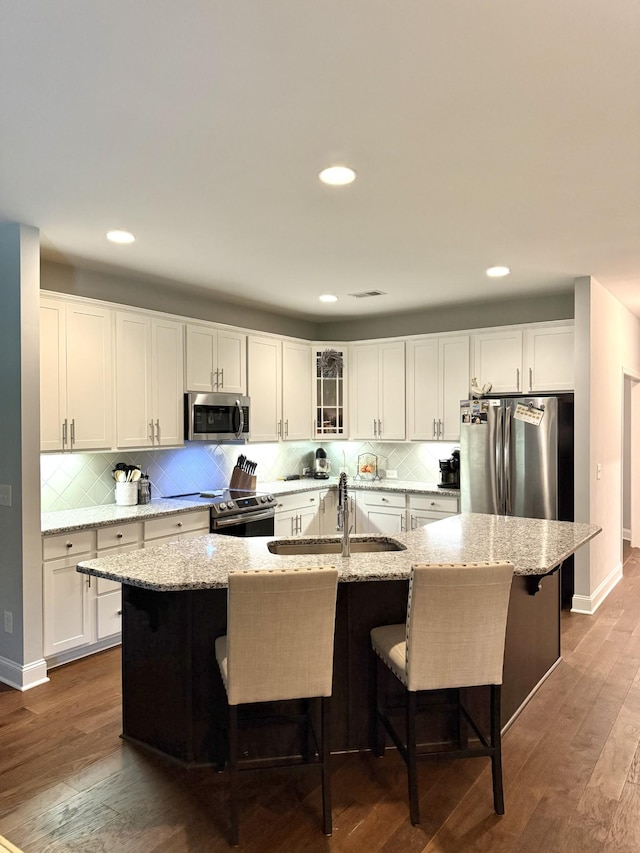 107 Auxley Ct, White House, TN 37188 - kitchen featuring stainless steel appliances, a sink, white cabinetry, tasteful backsplash, and a breakfast bar
