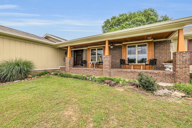 view of front facade featuring brick siding, a front lawn, a ceiling fan, and covered porch