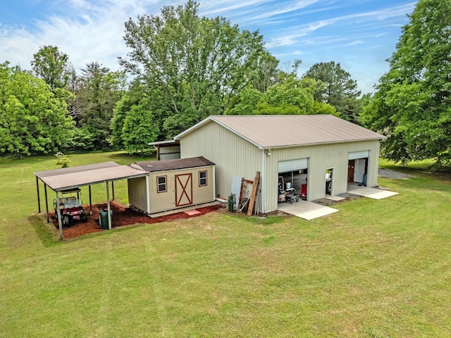 back of house with an outdoor structure, a detached garage, and a yard