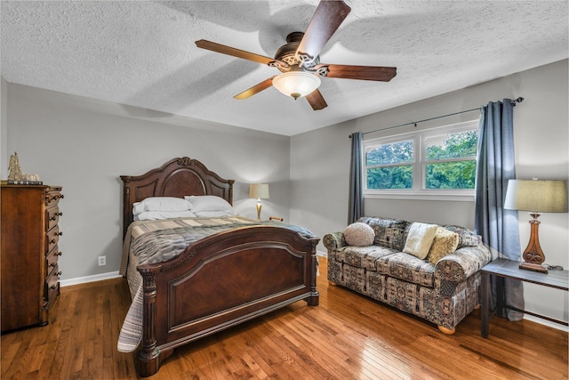 bedroom featuring wood-type flooring, baseboards, a textured ceiling, and ceiling fan