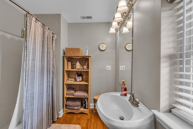 full bathroom featuring wood finished floors, a sink, a shower with shower curtain, and a chandelier