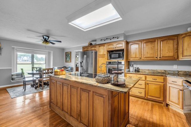 kitchen with black appliances, light wood-style flooring, stone counters, and ornamental molding