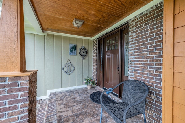 view of exterior entry featuring a porch and brick siding
