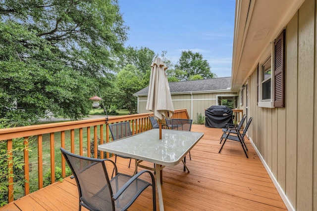 wooden terrace featuring outdoor dining space, area for grilling, and a lawn
