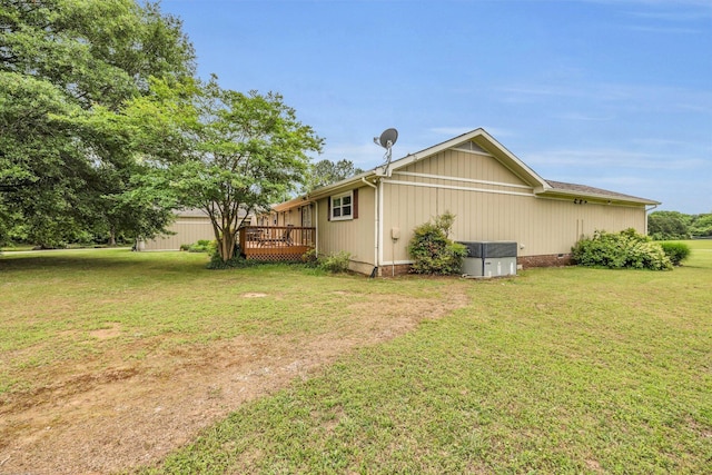 view of side of home with a wooden deck, a yard, and central AC unit