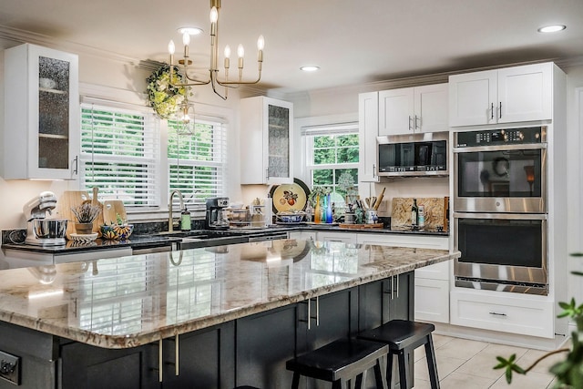 819 N Jefferson Ave, Cookeville, TN 38501 - kitchen featuring appliances with stainless steel finishes, white cabinets, light stone counters, a kitchen island, and ornamental molding
