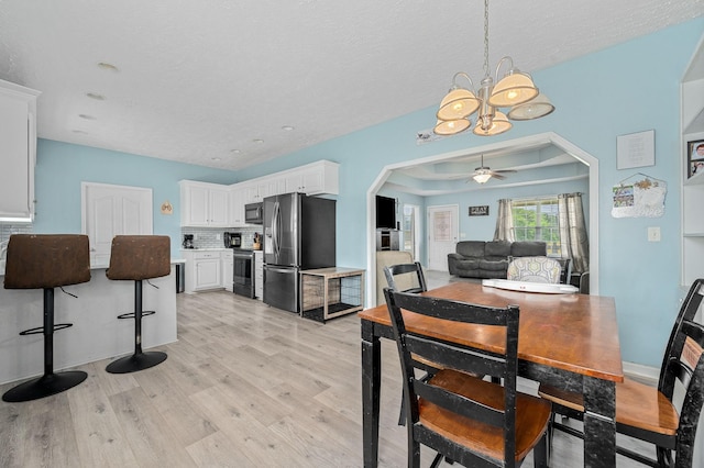 278 Riddle Rd, Manchester, TN 37355 - dining area featuring a chandelier, light wood finished floors, arched walkways, a ceiling fan, and a textured ceiling