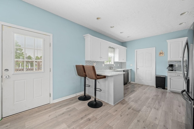 278 Riddle Rd, Manchester, TN 37355 - kitchen with decorative backsplash, white cabinetry, light countertops, a peninsula, and light wood-style flooring
