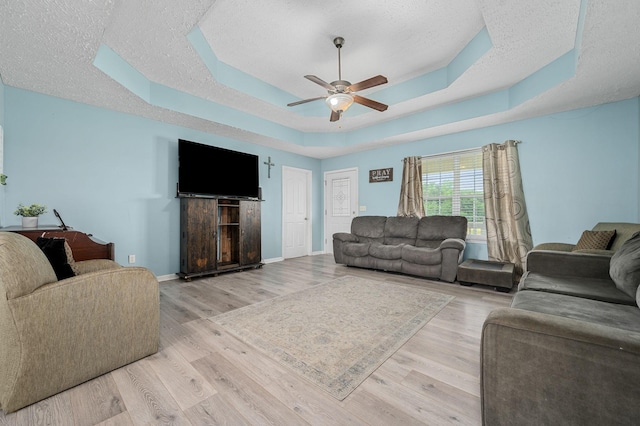 278 Riddle Rd, Manchester, TN 37355 - living area featuring a textured ceiling, a ceiling fan, a tray ceiling, light wood-type flooring, and baseboards
