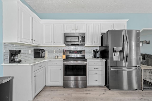 278 Riddle Rd, Manchester, TN 37355 - kitchen with stainless steel appliances, light countertops, light wood-style floors, white cabinets, and backsplash