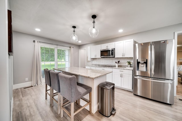 1112 Belmont Dr, Cookeville, TN 38506 - kitchen featuring stainless steel appliances, white cabinets, light wood finished floors, a kitchen island, and decorative backsplash