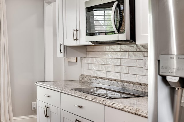 1112 Belmont Dr, Cookeville, TN 38506 - kitchen featuring stainless steel microwave, decorative backsplash, white cabinets, black electric cooktop, and light stone countertops