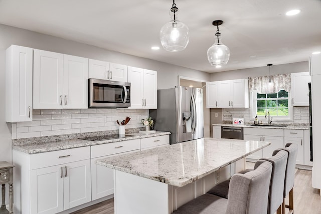 1112 Belmont Dr, Cookeville, TN 38506 - kitchen with appliances with stainless steel finishes, a sink, a kitchen breakfast bar, light wood-type flooring, and tasteful backsplash