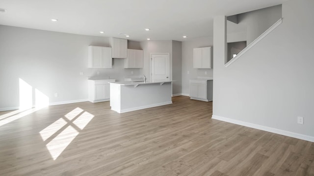4028 Roane Dr, White House, TN 37188 - kitchen with a center island with sink, white cabinets, baseboards, light wood-type flooring, and open floor plan
