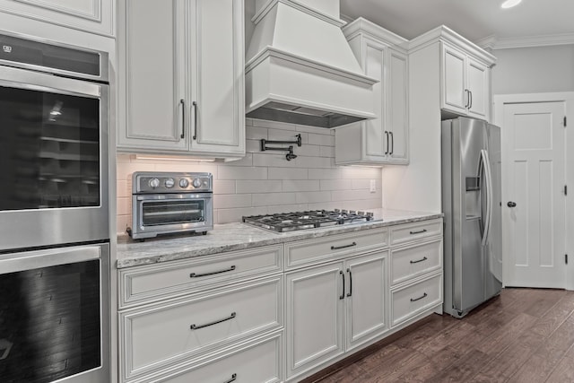 512 River Watch Way, Winchester, TN 37398 - kitchen featuring appliances with stainless steel finishes, custom exhaust hood, backsplash, dark wood-type flooring, and white cabinetry