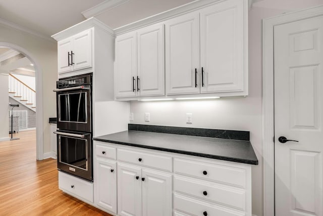 316 Whitworth Way, Nashville, TN 37205 - kitchen featuring dark countertops, arched walkways, light wood finished floors, white cabinets, and crown molding