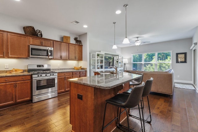 864 Meadowcrest Way Unit 823, Lebanon, TN 37090 - kitchen with appliances with stainless steel finishes, dark wood finished floors, stone counters, a breakfast bar, and brown cabinets