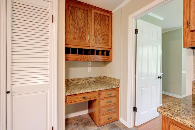 339 Thompson Ln, Clarksville, TN 37040 - kitchen with crown molding, brown cabinetry, light stone countertops, and baseboards