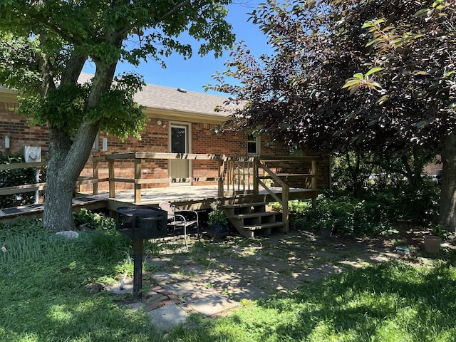 rear view of house with brick siding, a deck, and roof with shingles