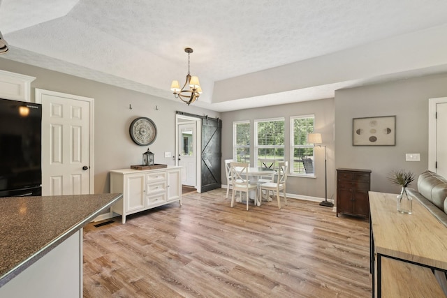 2277 Belotes Ferry Rd, Lebanon, TN 37087 - dining space with light wood-style flooring, a textured ceiling, a chandelier, baseboards, and a barn door