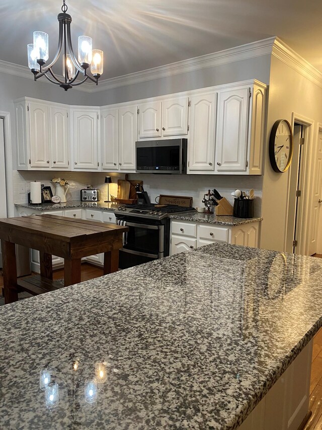 415 Ashley Ln, Kingston Springs, TN 37082 - kitchen with appliances with stainless steel finishes, ornamental molding, white cabinets, a chandelier, and dark stone counters