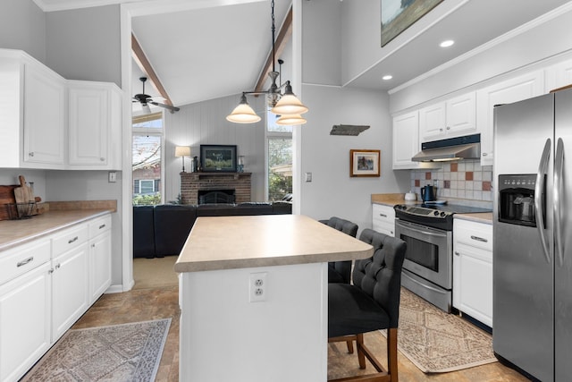 209 Woods Dr, Columbia, TN 38401 - kitchen with appliances with stainless steel finishes, under cabinet range hood, a center island, a brick fireplace, and backsplash