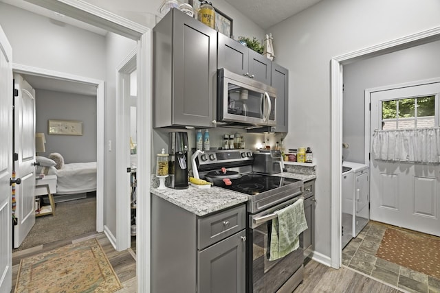 103 Lockhart St, Dickson, TN 37055 - kitchen featuring appliances with stainless steel finishes, gray cabinets, washer and dryer, and light stone counters