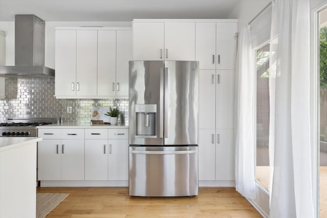 814A Horner Ave, Nashville, TN 37204 - kitchen featuring stainless steel refrigerator with ice dispenser, wall chimney range hood, tasteful backsplash, light countertops, and light wood-style floors