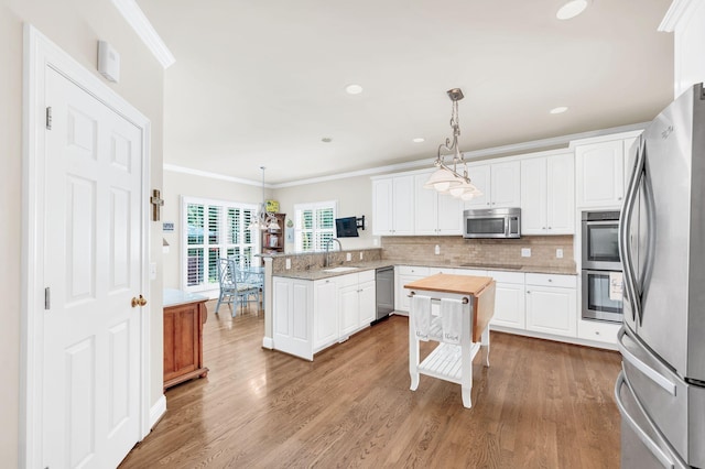 113 Abbeywood Dr, Nashville, TN 37215 - kitchen featuring stainless steel appliances, a peninsula, ornamental molding, a sink, and white cabinetry