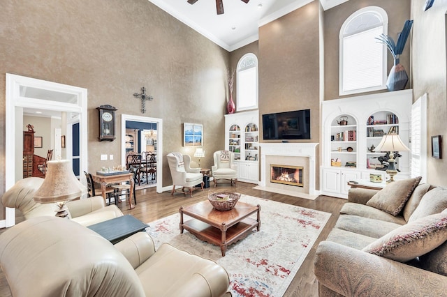 113 Abbeywood Dr, Nashville, TN 37215 - living room featuring a towering ceiling, crown molding, ceiling fan, built in shelves, and a fireplace with flush hearth
