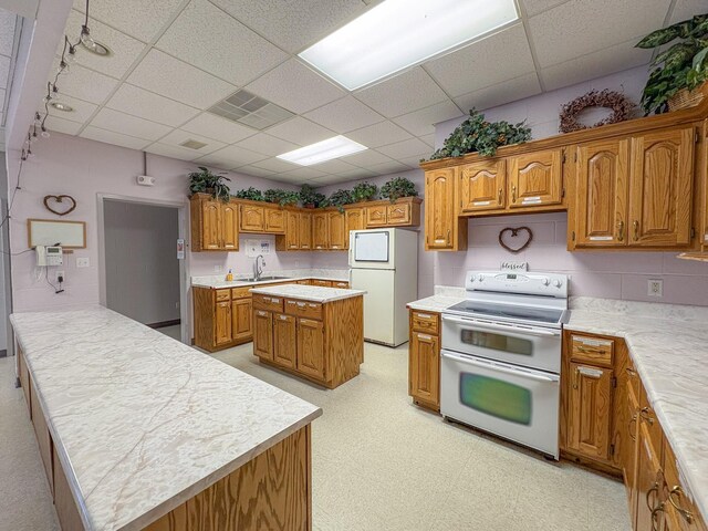 110 Hankins Rd, Hohenwald, TN 38462 - kitchen with white appliances, a drop ceiling, brown cabinets, light countertops, and a sink