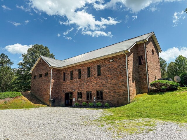 110 Hankins Rd, Hohenwald, TN 38462 - view of property exterior with brick siding, driveway, a lawn, and metal roof