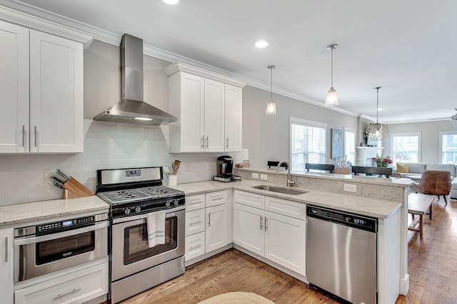 6214A California Ave, Nashville, TN 37209 - kitchen featuring stainless steel appliances, wall chimney exhaust hood, a sink, ornamental molding, and a peninsula