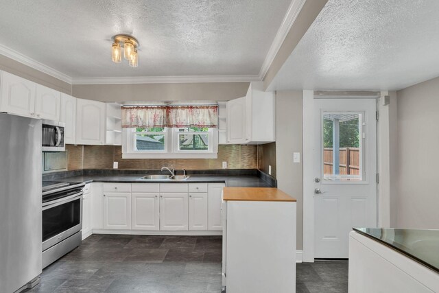 521 E Eastland St, Gallatin, TN 37066 - kitchen featuring appliances with stainless steel finishes, a textured ceiling, a sink, healthy amount of natural light, and dark countertops