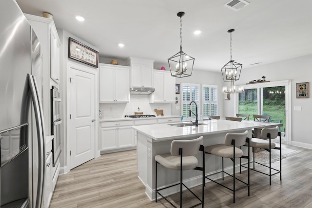 3706 Bonnie Blue Ct, Rockvale, TN 37153 - kitchen with appliances with stainless steel finishes, a sink, under cabinet range hood, a center island with sink, and light wood-style floors