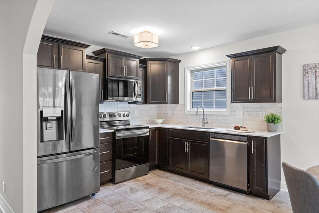 1021 Charles Thomas Dr, Clarksville, TN 37042 - kitchen featuring stainless steel appliances, a sink, backsplash, and dark brown cabinetry