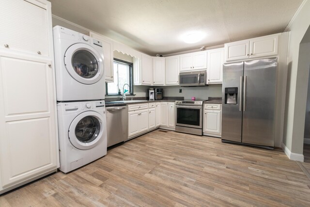 104 3rd Ave NW, Winchester, TN 37398 - kitchen featuring stainless steel appliances, stacked washing machine and dryer, dark countertops, light wood-style floors, and a sink